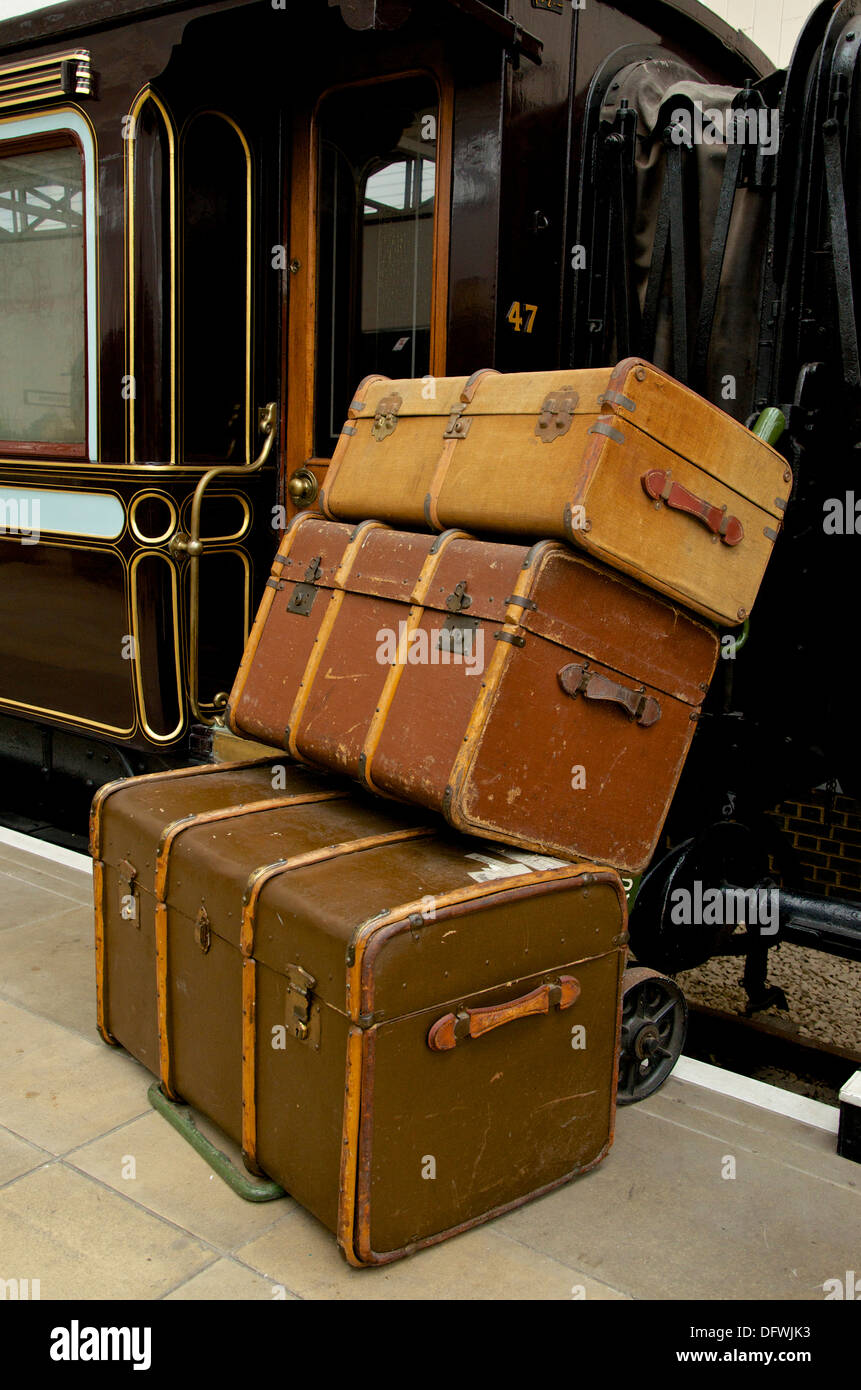 Traditional traveling trunks on a hand trolley alongside a gilded LNWR First Class sleeping railway coach. Stock Photo