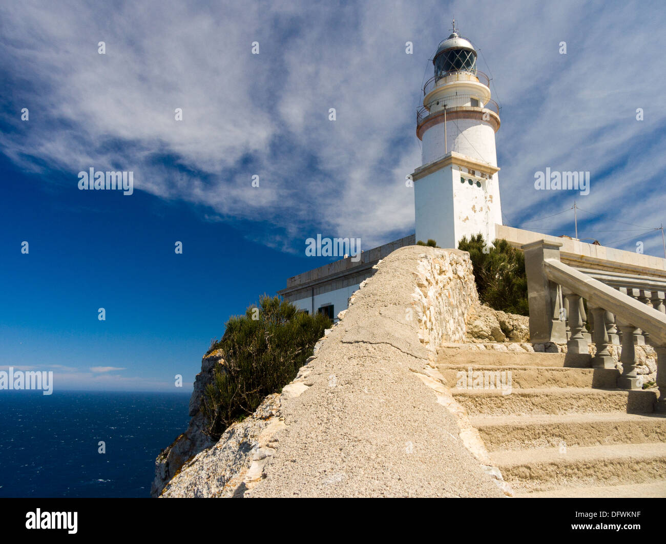 White lighthouse with steps and sea at the point of Cap de Formentor, Mallorca, with whispy clouds taken with polarising filter. Stock Photo