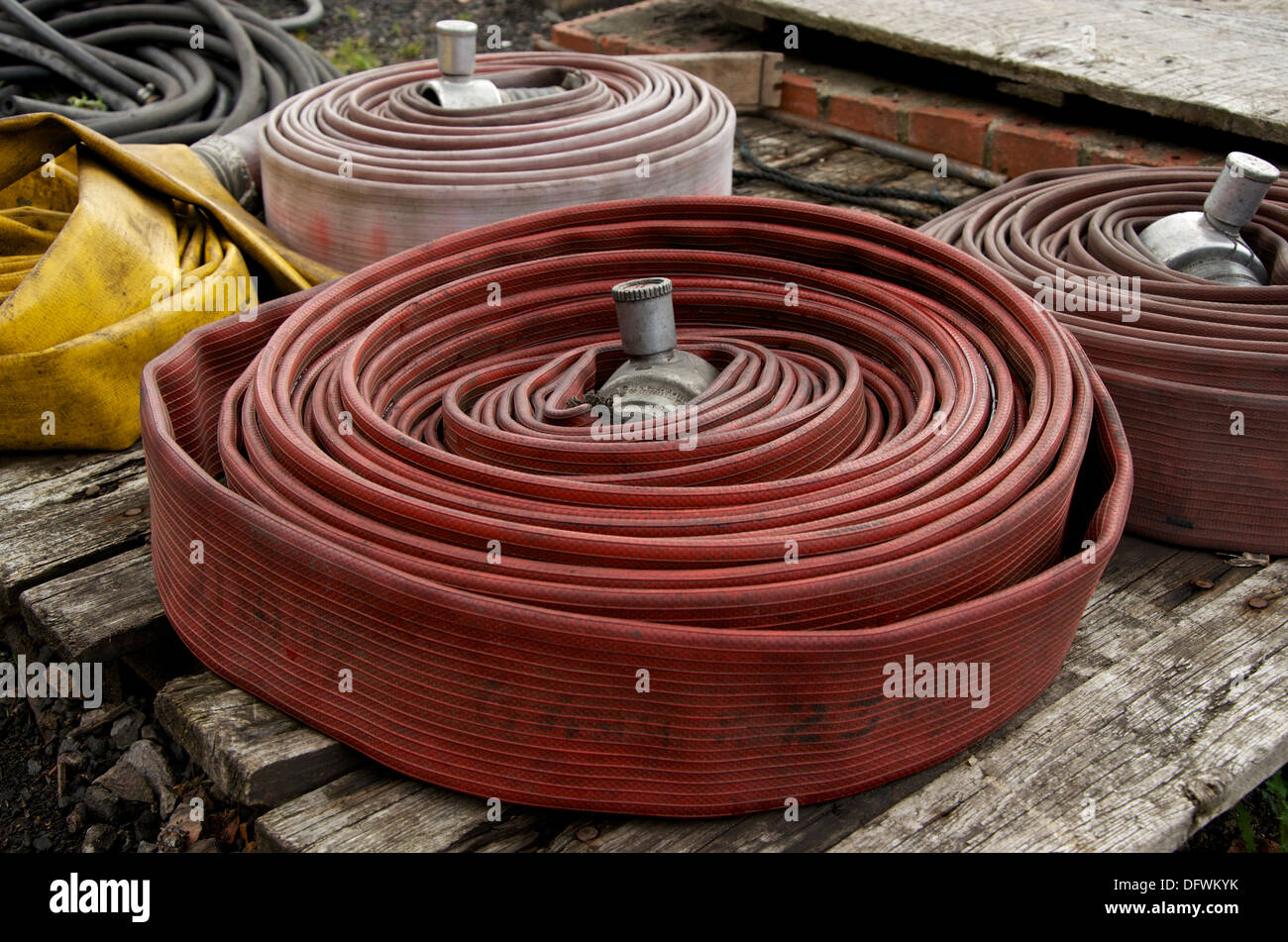 Old industrial water hoses neatly rolled on a wooden pallet ready for