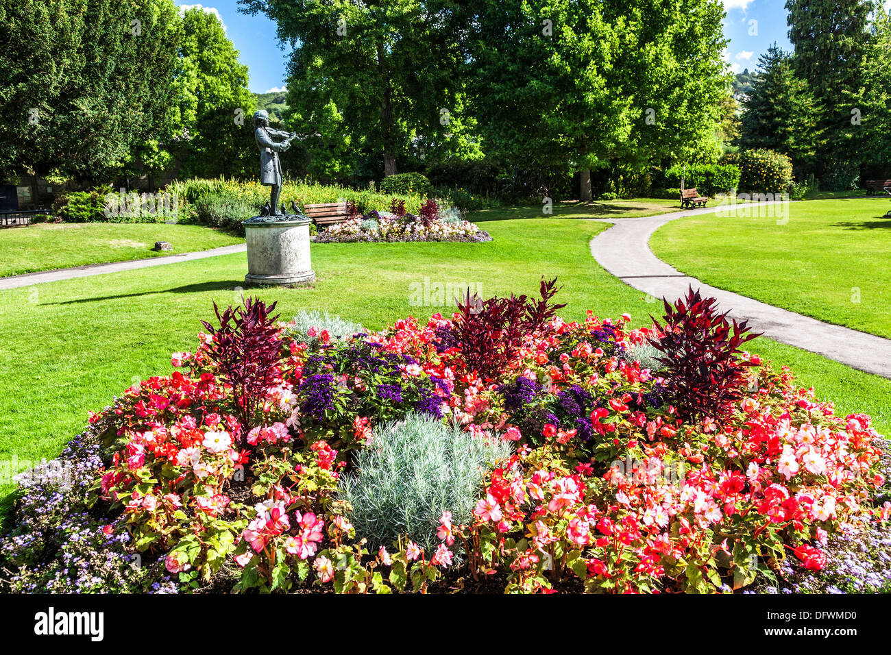 A flower bed in the Parade Gardens in Bath with the bronze statue of the young Mozart playing his violin in the background. Stock Photo