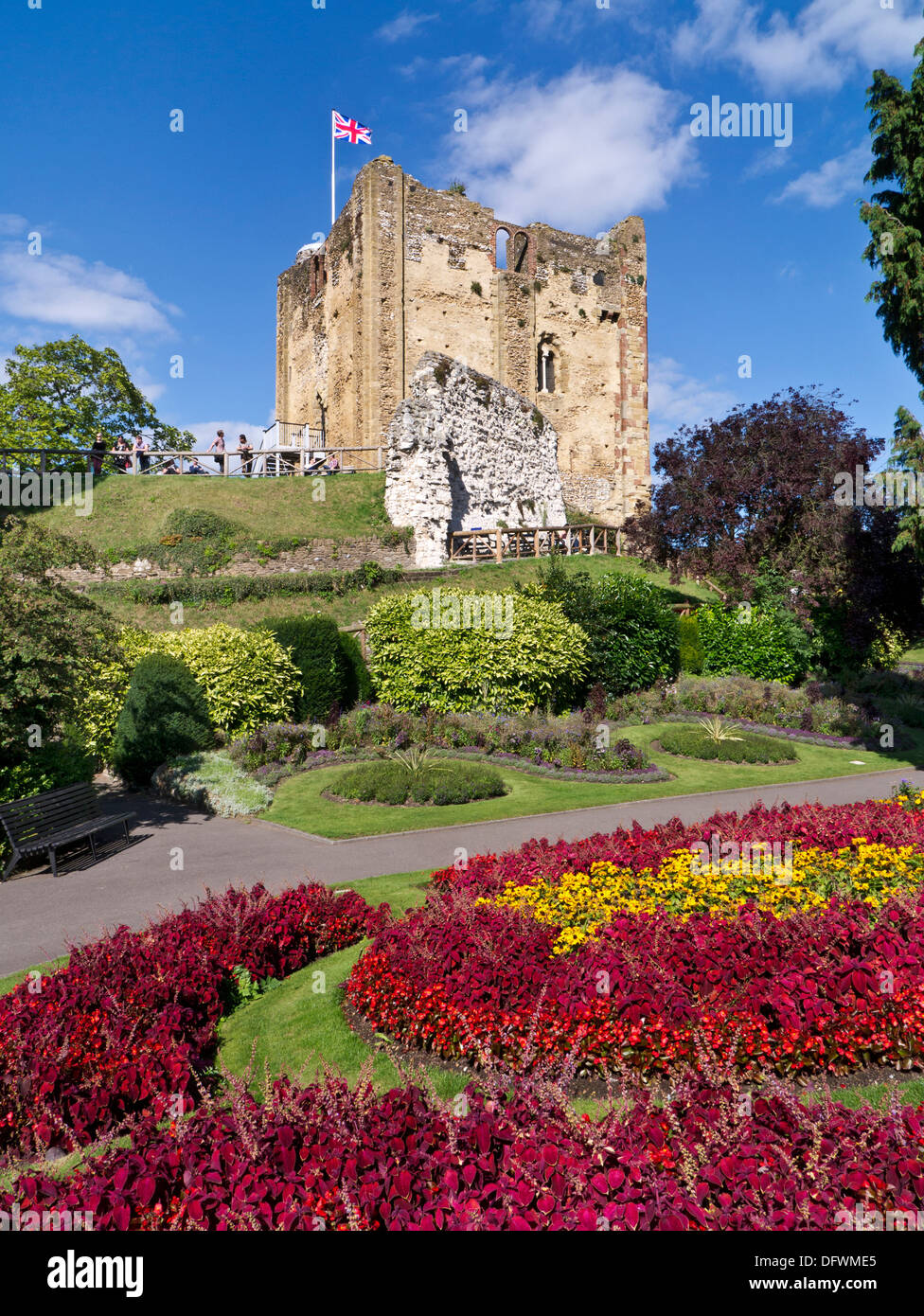 Guildford Castle flying the Union Jack flag with formal summer gardens floral colour in foreground Guildford Surrey UK Stock Photo