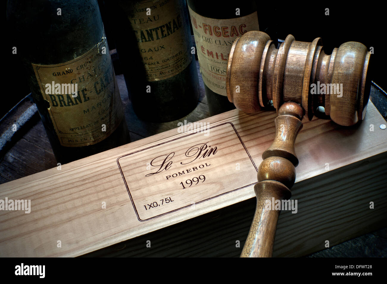 Wine auction situation with auctioneers gavel on 1999 Chateau Le Pin wine bottle box old Bordeaux bottles behind Bordeaux France Stock Photo