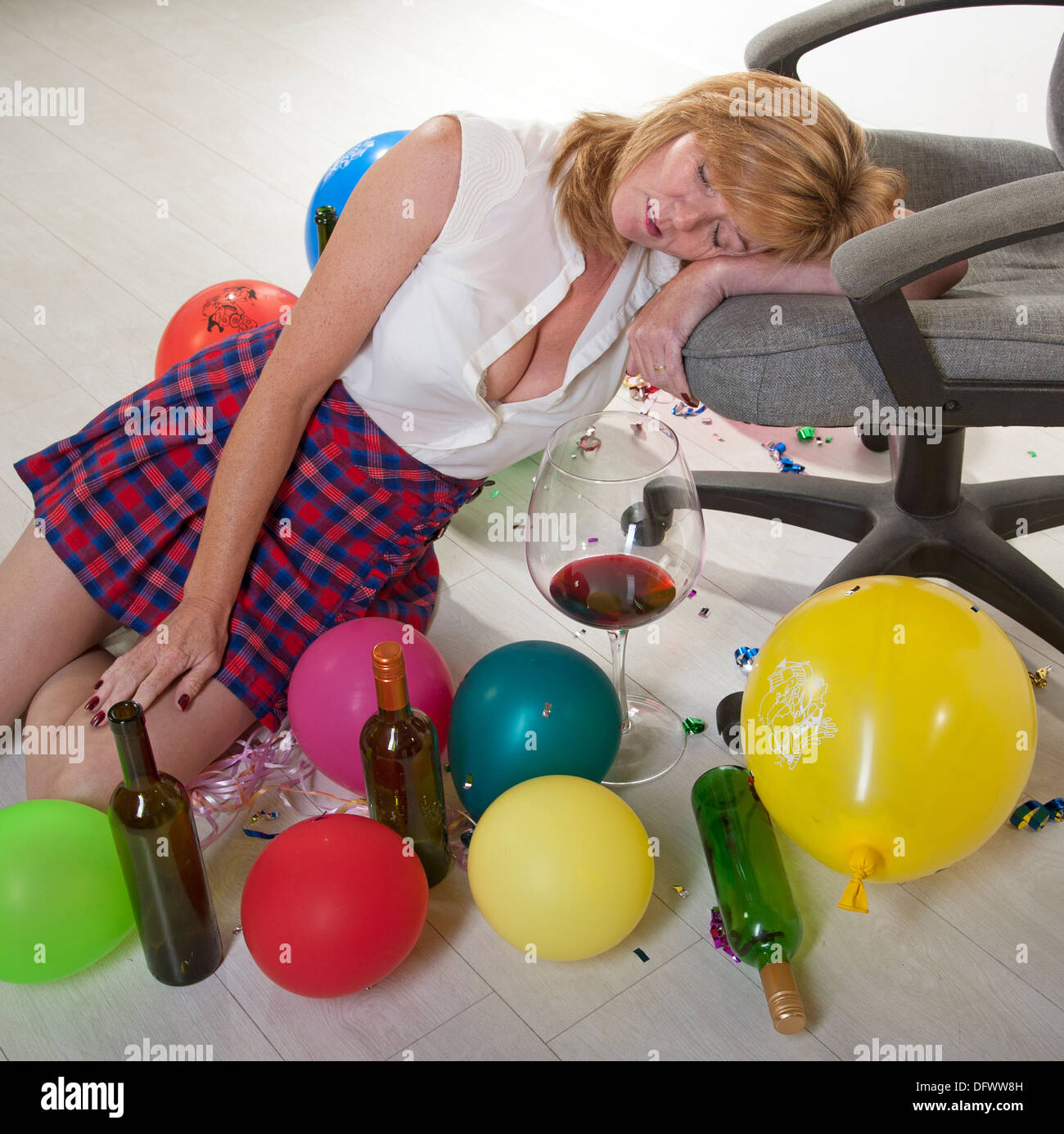 Female office party goer sleeping off the effects of alcohol using a swivel chair Stock Photo
