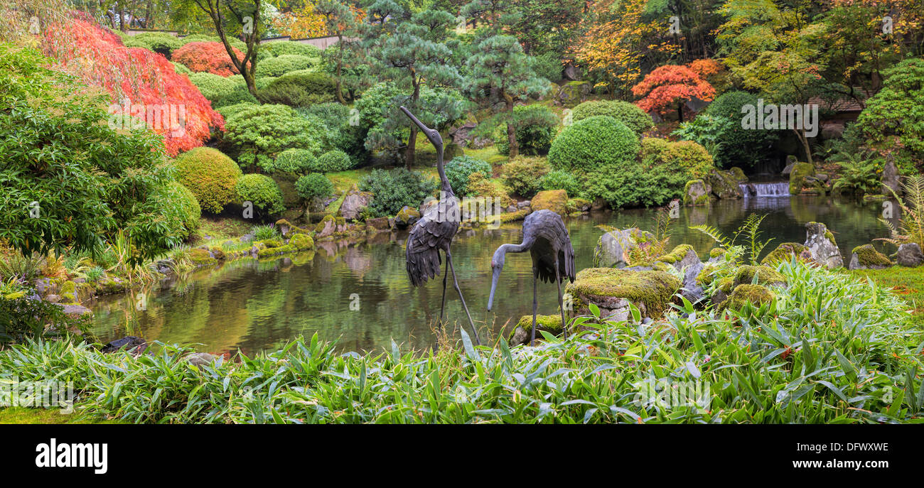 Japanese Bronze Cranes Sculpture Pair by Water Pond with Trees Plants and Shrubs in the Fall Panorama Stock Photo