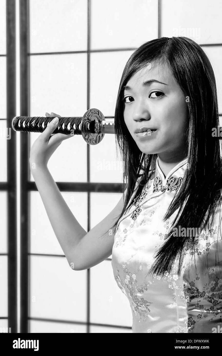 An Asian girl in a kimono holding a samurai sword in black and white Stock Photo
