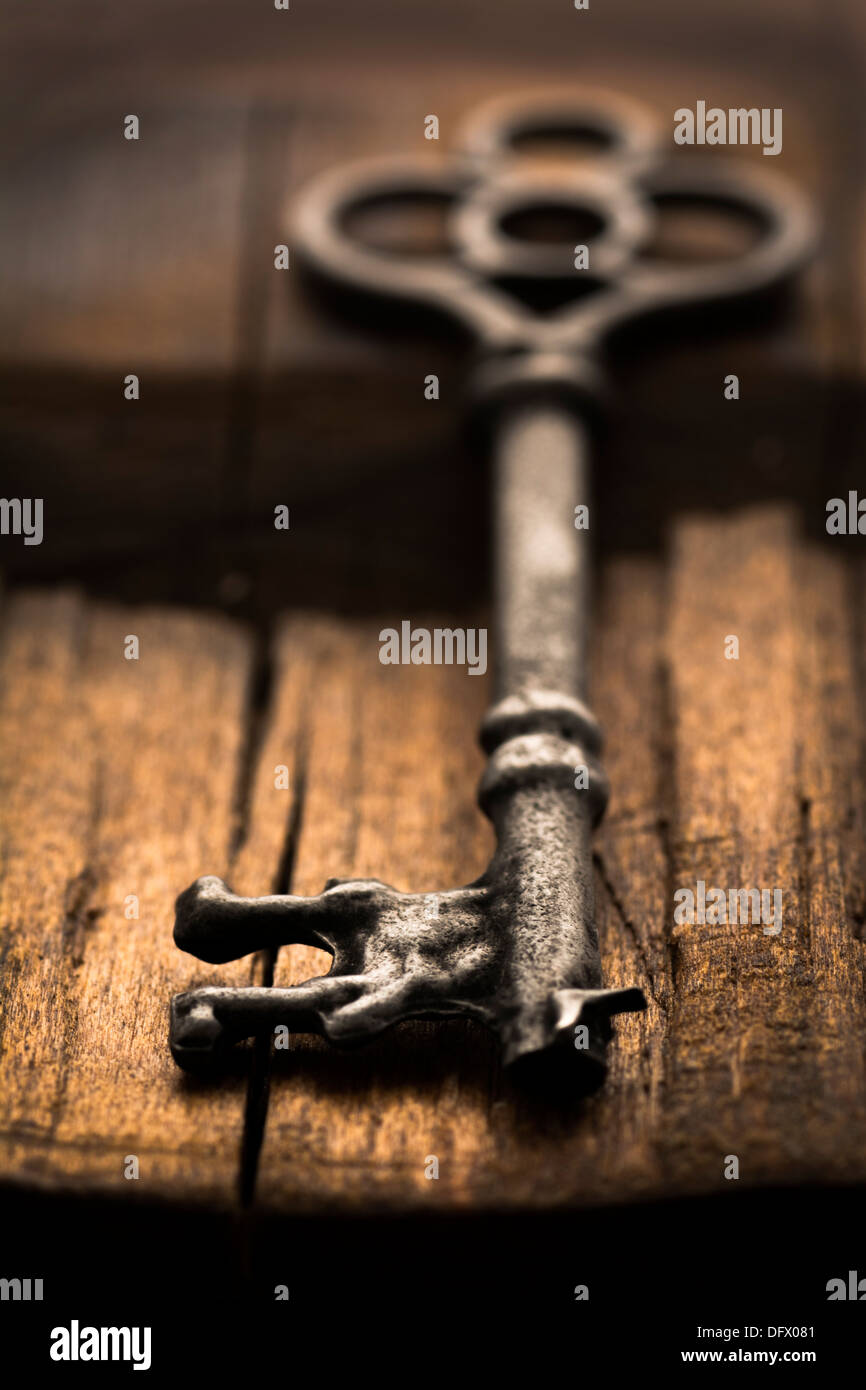 Old ornate skeleton key on rough wood background with selective focus Stock Photo