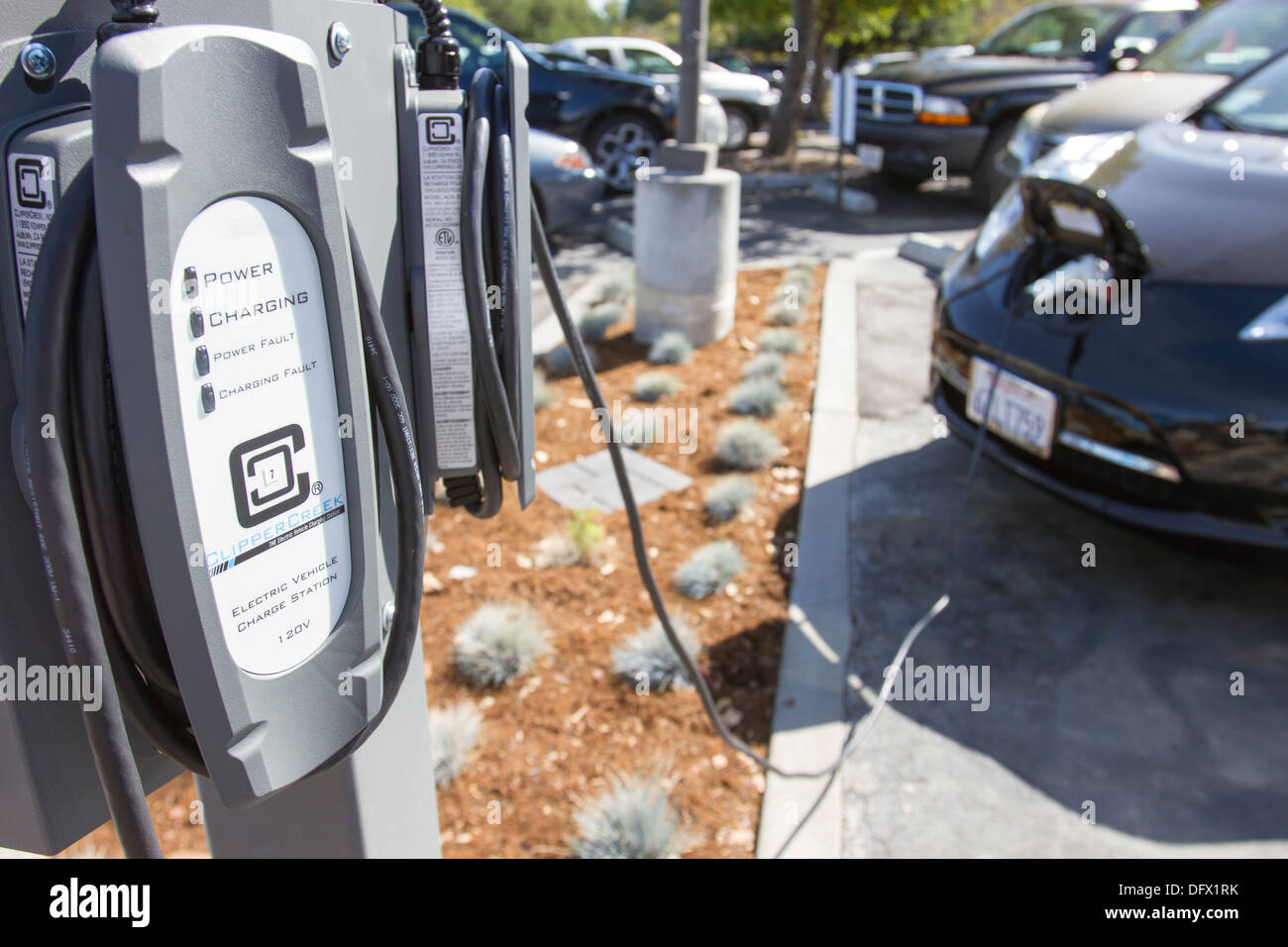 EV charging stations with plug-in electric car plugged in to charge its batteries in at a company parking lot Stock Photo