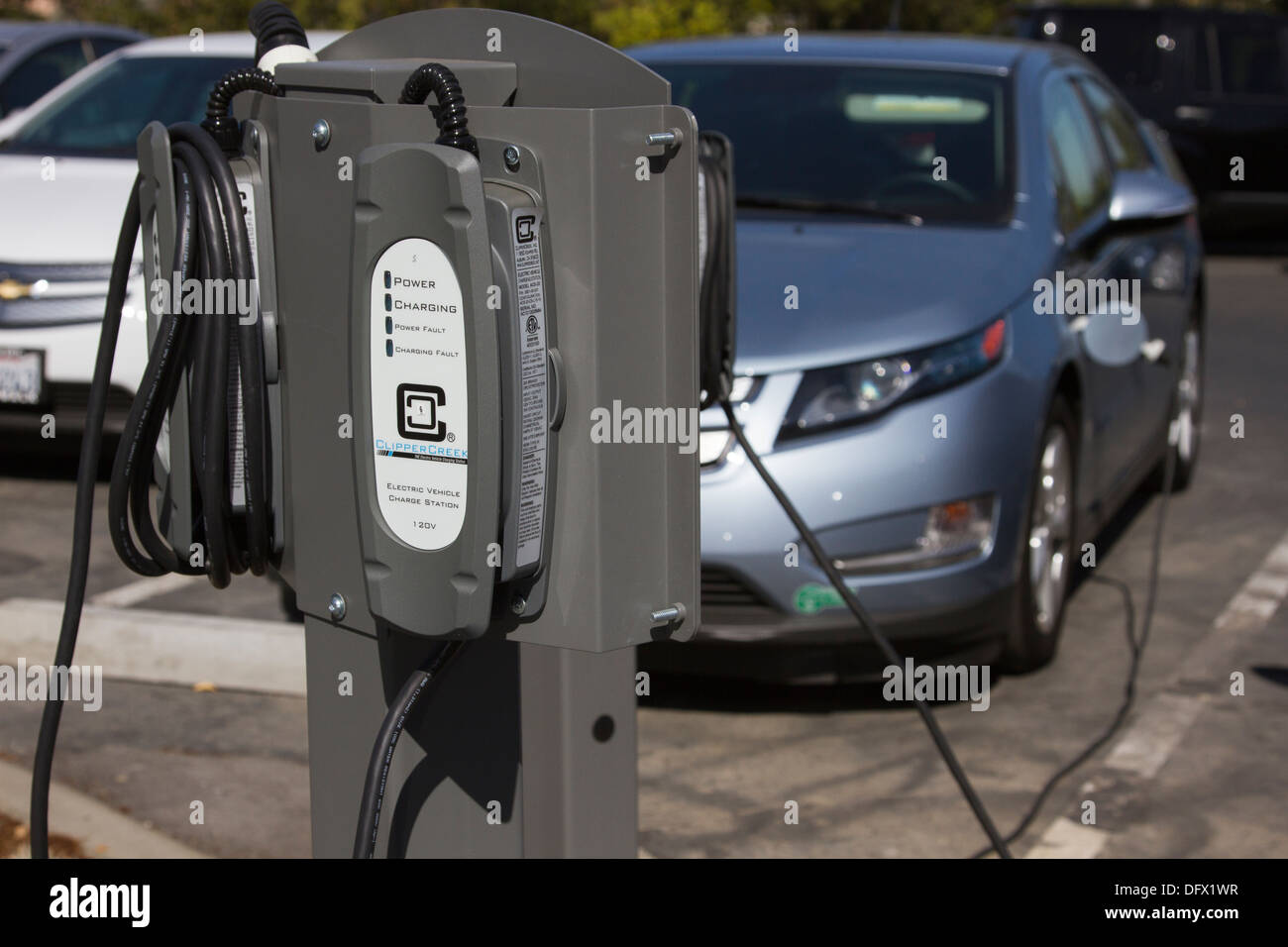 EV charging stations with plug-in electric car plugged and charging in at a company parking lot Stock Photo