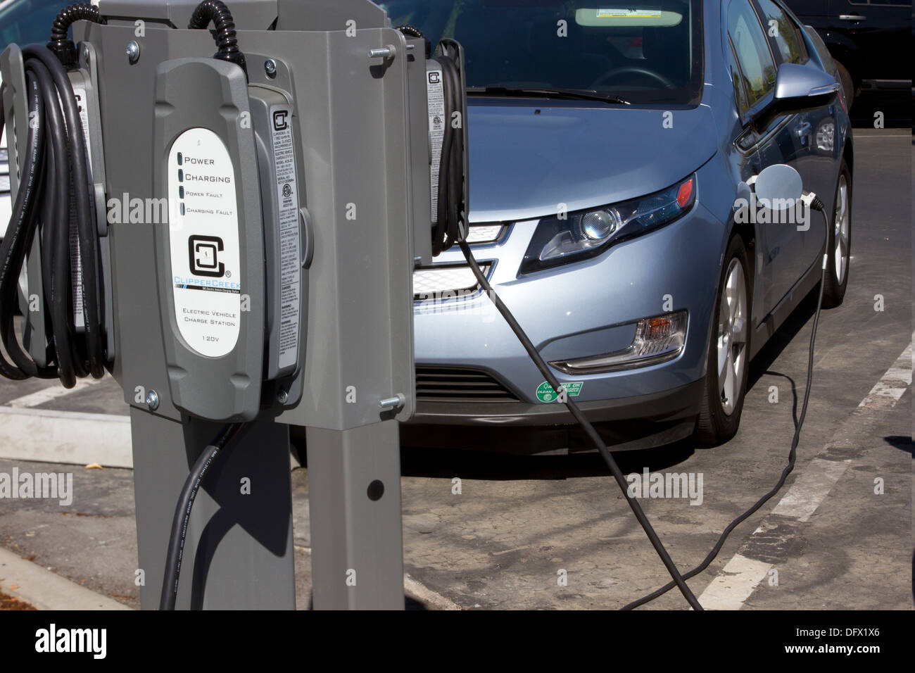 EV charging stations with plug-in electric car plugged to charge its battery in a workplace parking lot Stock Photo