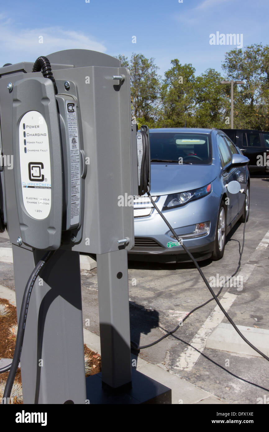 Plug-in electric car plugged into EV charging stations to charge its batteries in a workplace parking lot Stock Photo