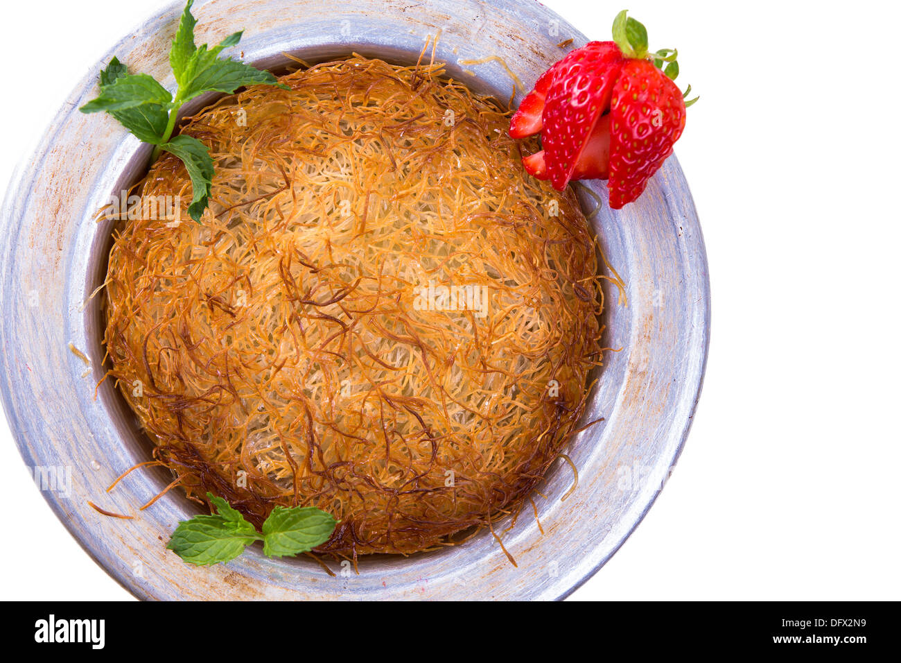 Turkish dessert kunefe isolated on a white background with mints and sliced strawberry Stock Photo