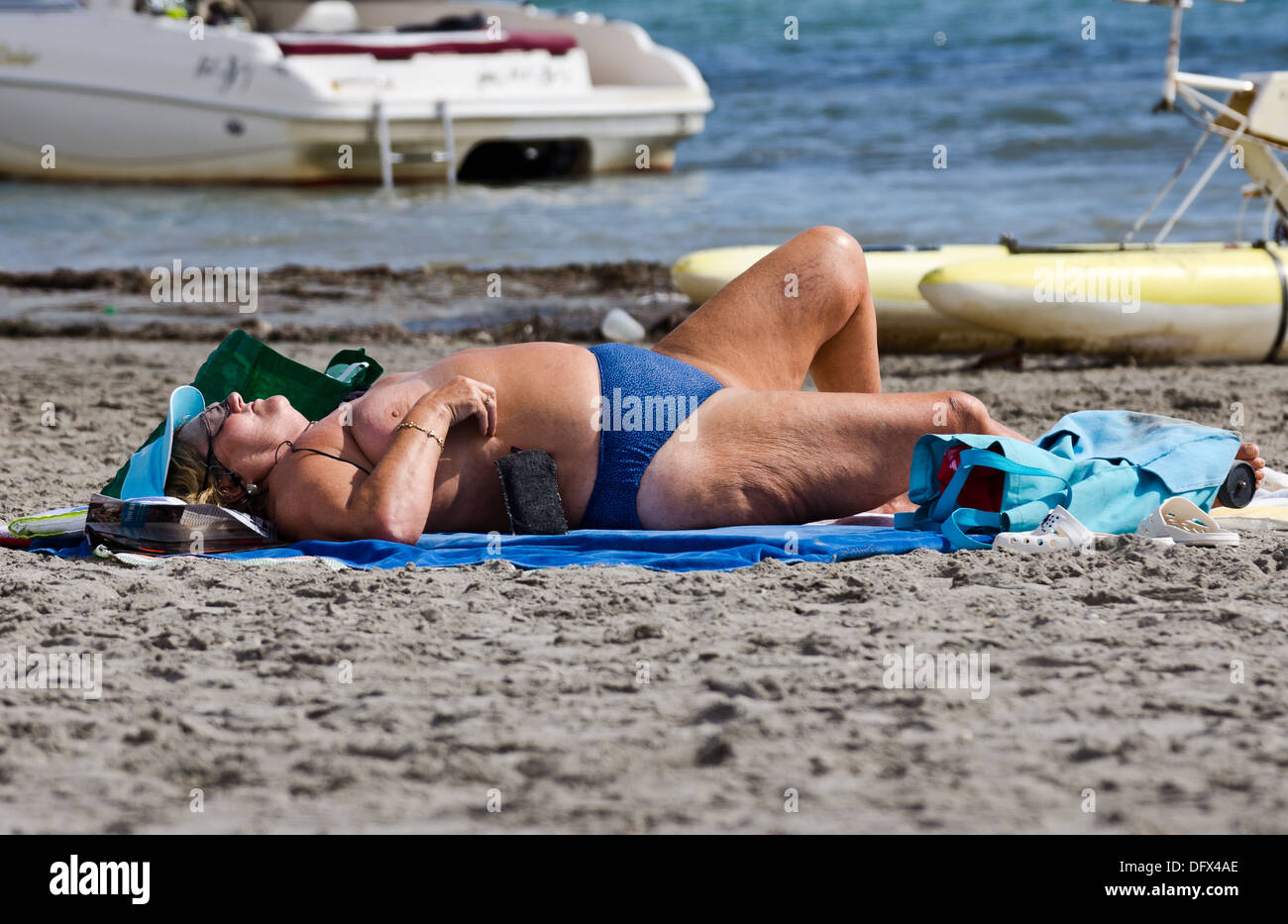Obese lady sunbathing on the beach in Spain Stock Photo