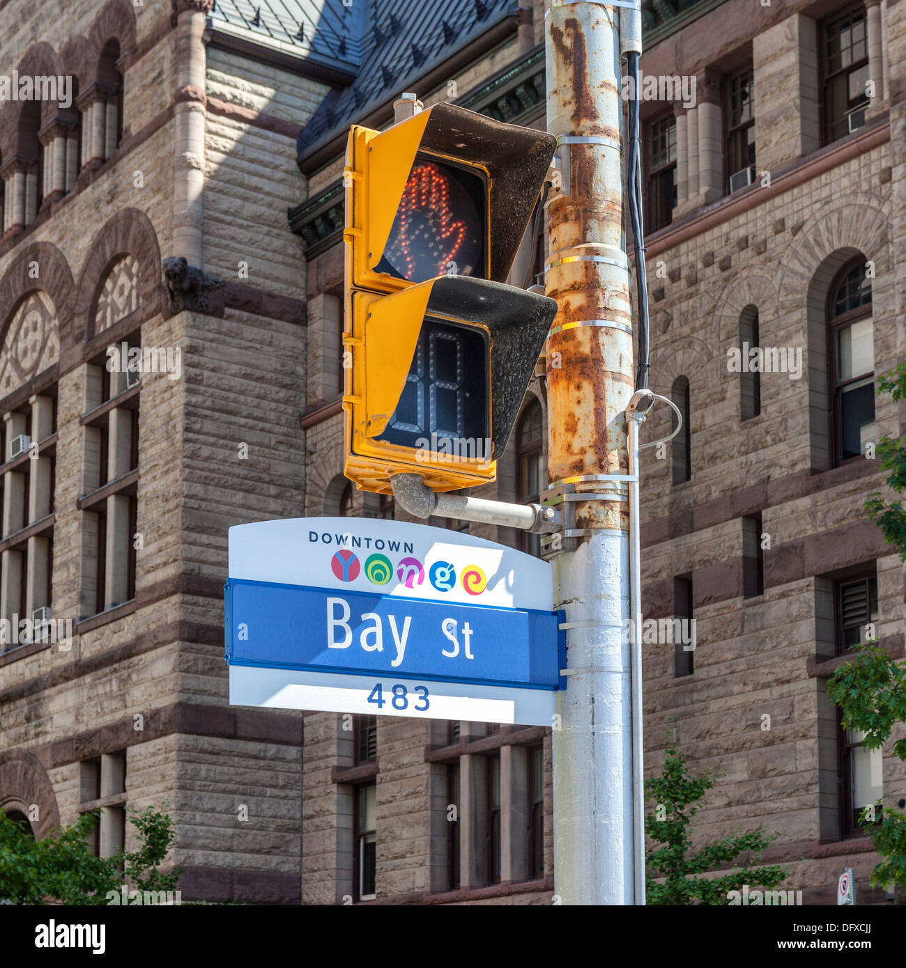 Downtown Yonge, Bay Street sign and yellow pedestrian crossing light with sand stone old city hall in background, Toronto Stock Photo