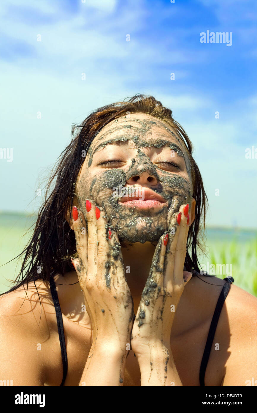 Beautiful young woman taking mud bath outdoors Stock Photo - Alamy