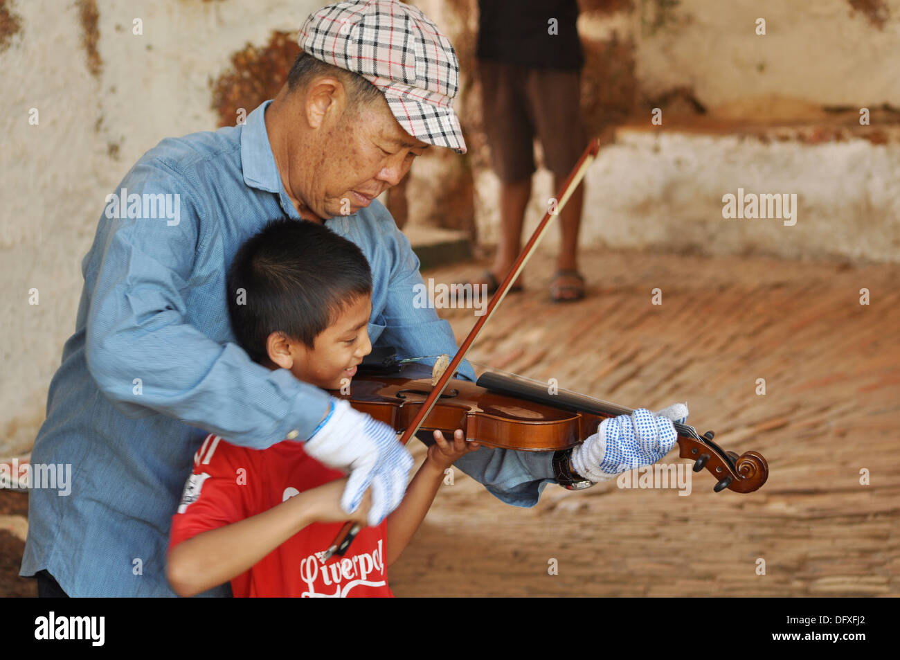 Malacca Malaysia A Chinese Malay Man Teaching A Indian Malay Kid To Play Violin Inside The Porta De Santiago Stock Photo Alamy