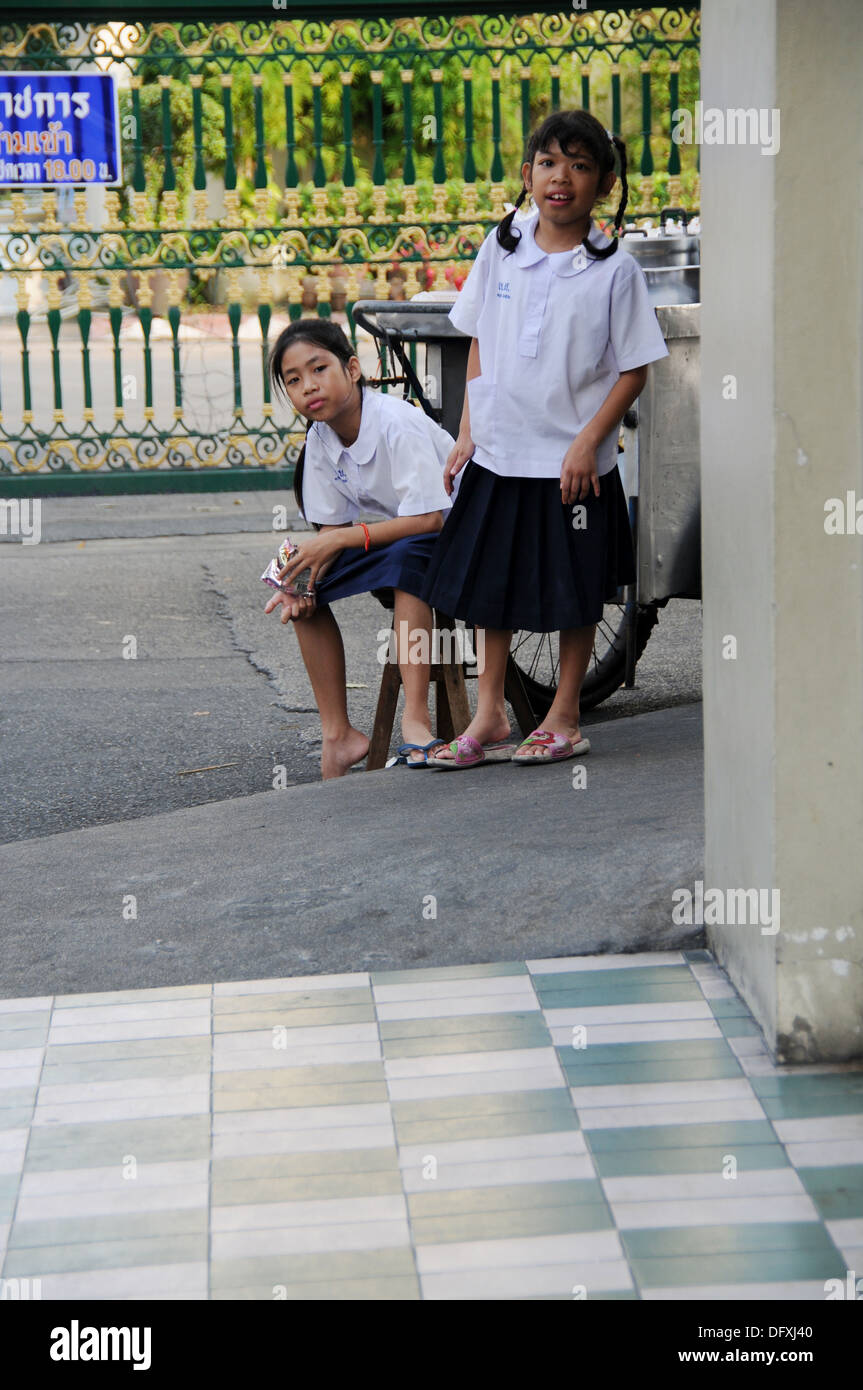 Two Schoolgirls waiting after School on a House Corner Stock Photo
