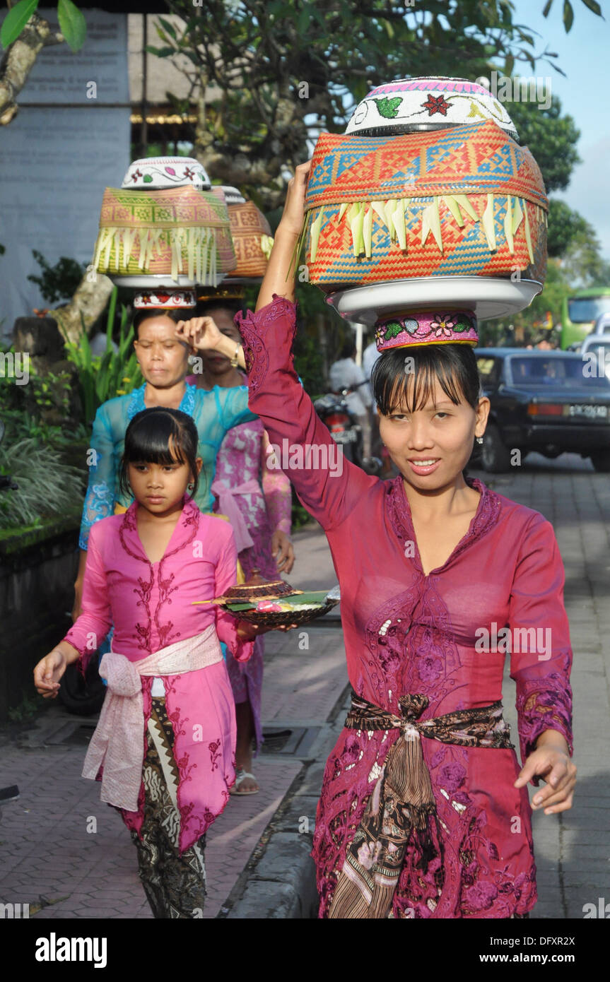 Ubud (Bali, Indonesia): women in traditional dress, carrying a basket with  offerings on their heads, going to a ceremony in a Stock Photo - Alamy