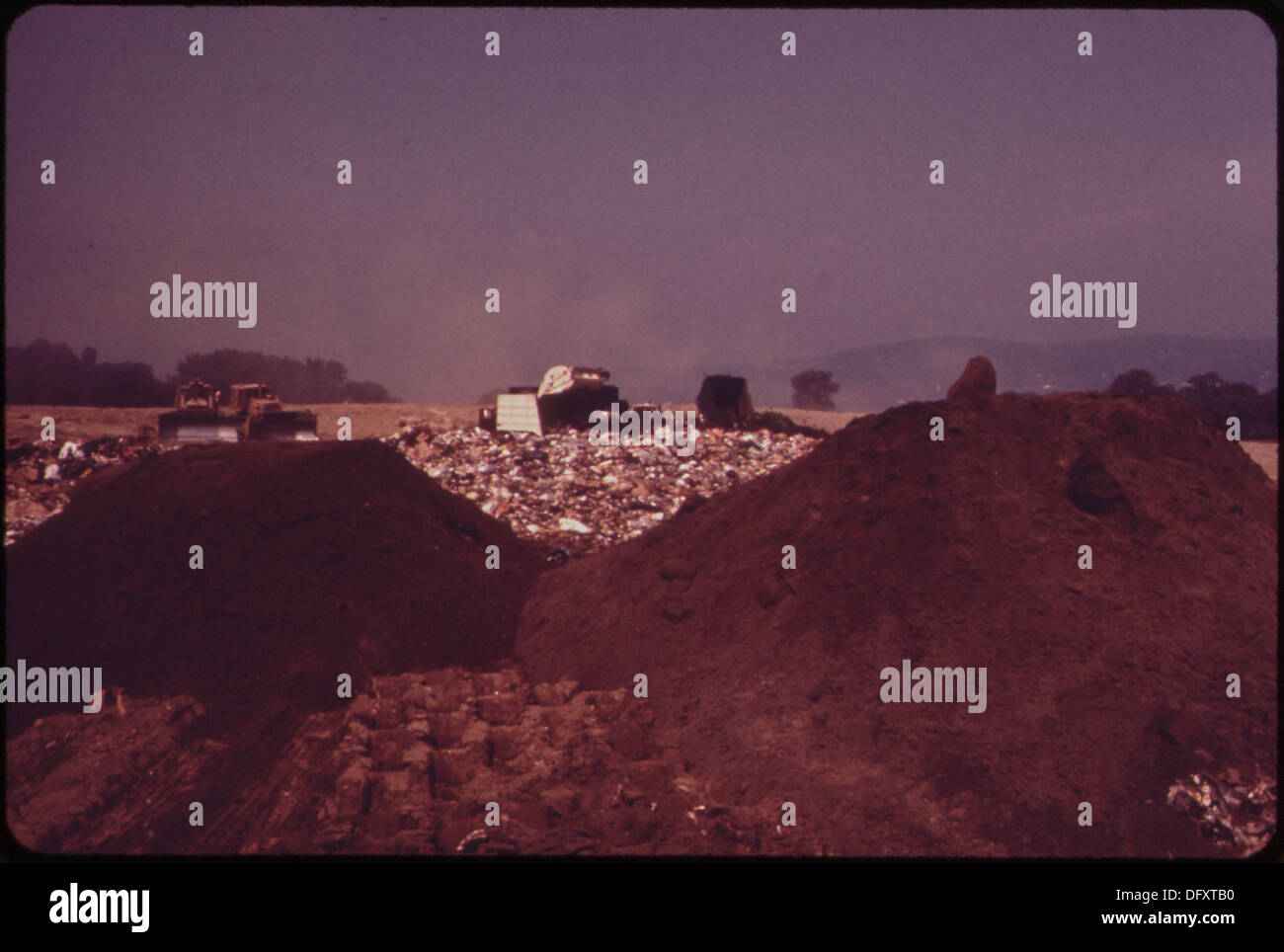 TRUCKS DUMP EARTH FILL OVER GARBAGE AT LANDFILL OPERATION IN CROTON