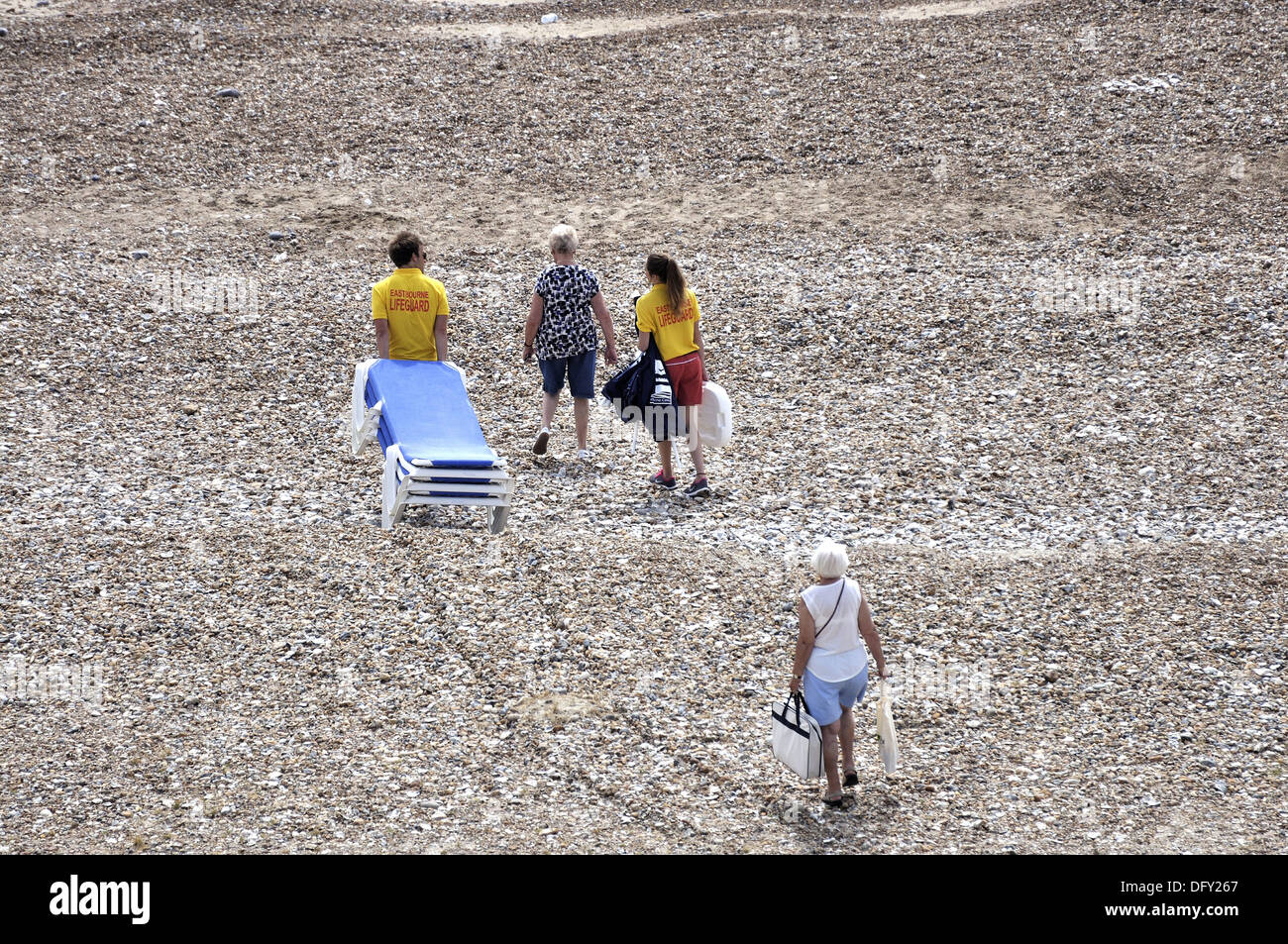 Eastbourne lifeguards dragging sun loungers down the beach with two