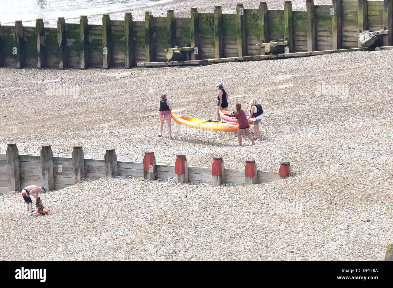 Four females carrying two kayaks down towards the sea on Eastbourne