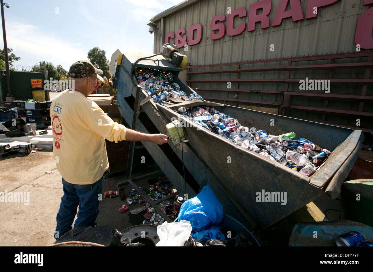 Male employee uses machine to crush aluminum cans at a metal recycling company in Texas Stock