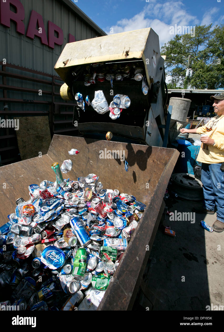 Male employee uses machine to crush aluminum cans at a metal recycling company in Texas Stock