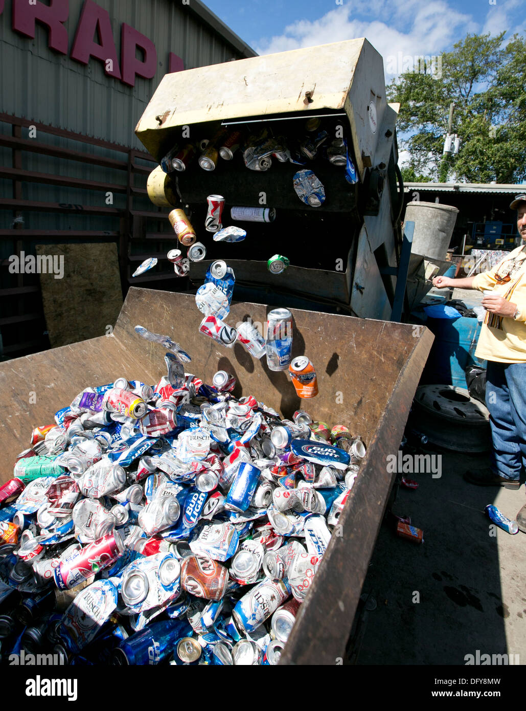 Male employee uses machine to crush aluminum cans at a metal recycling