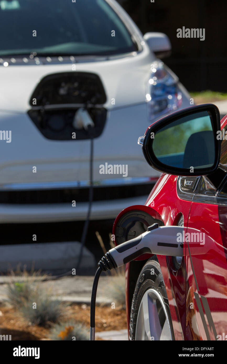 Red plugin electric car with connector plugged into a charging station