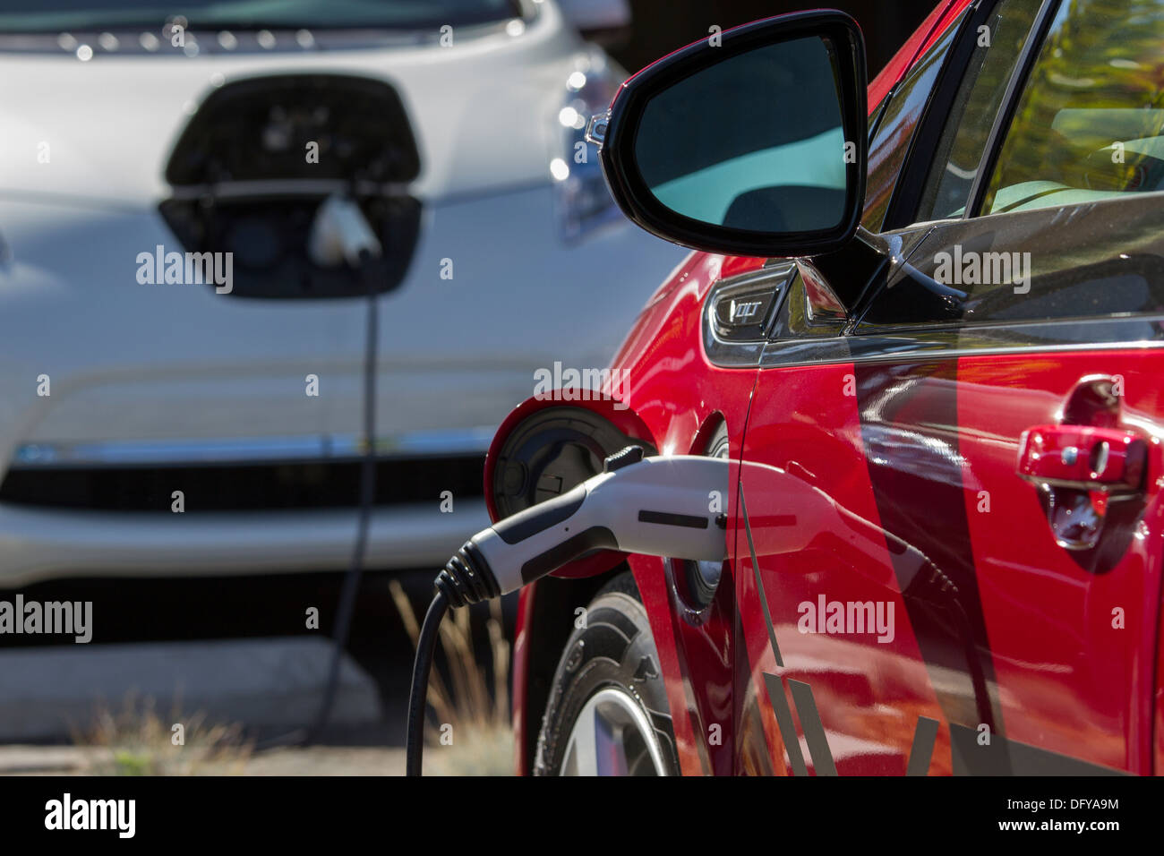 Red plugin electric car plugged into an EV charging station to charge