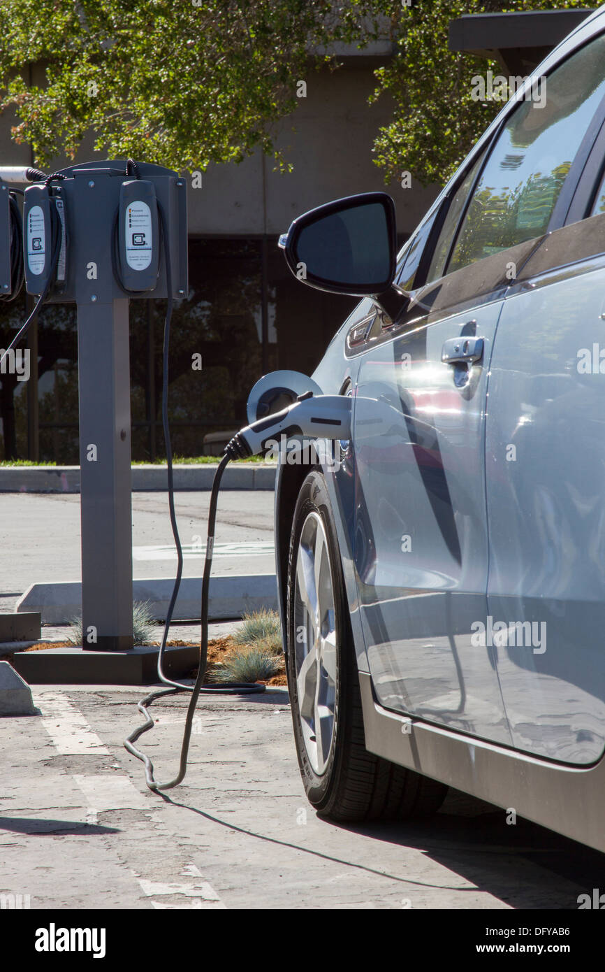 Plugin electric car with connector plugged into an EV charging station