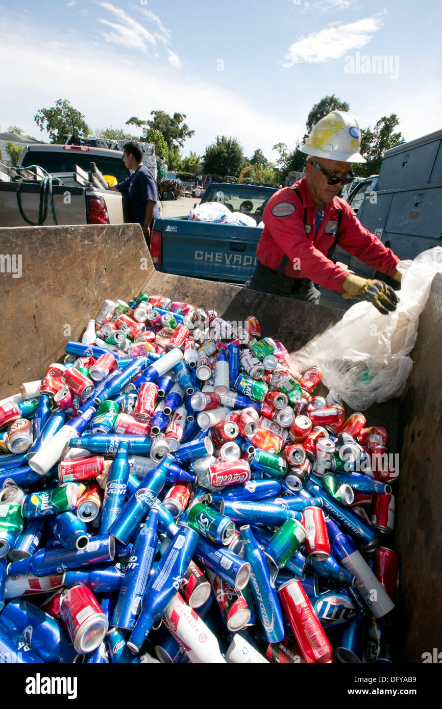 Worker at scrap metal recycling plant empties bag of cans, beer cans, soda cans in Texas Stock Photo