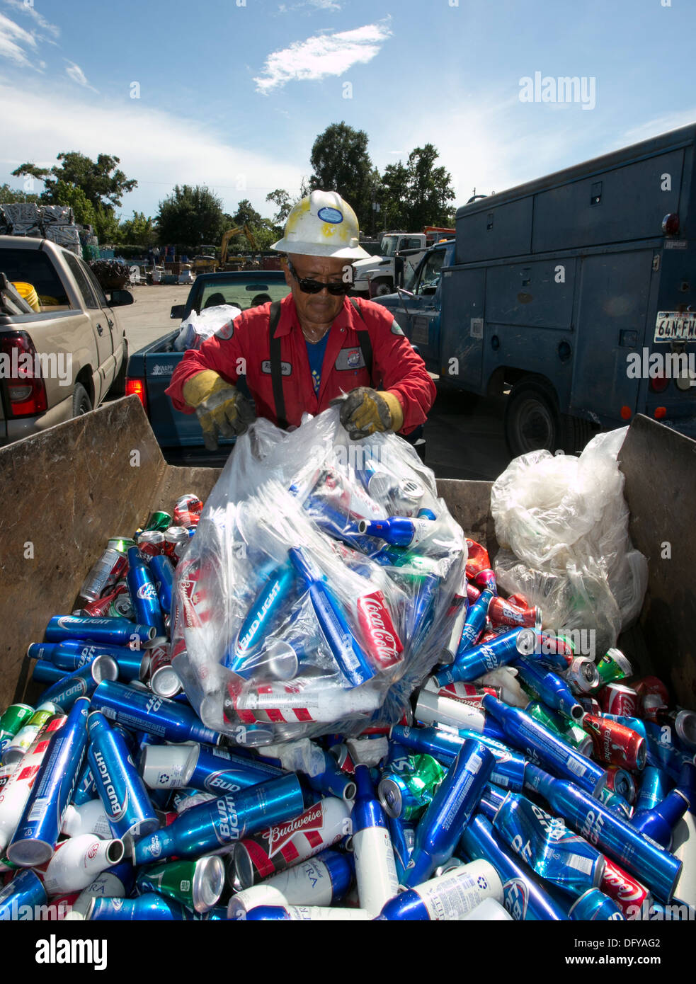 Worker at scrap metal recycling plant empties bag of cans, beer cans