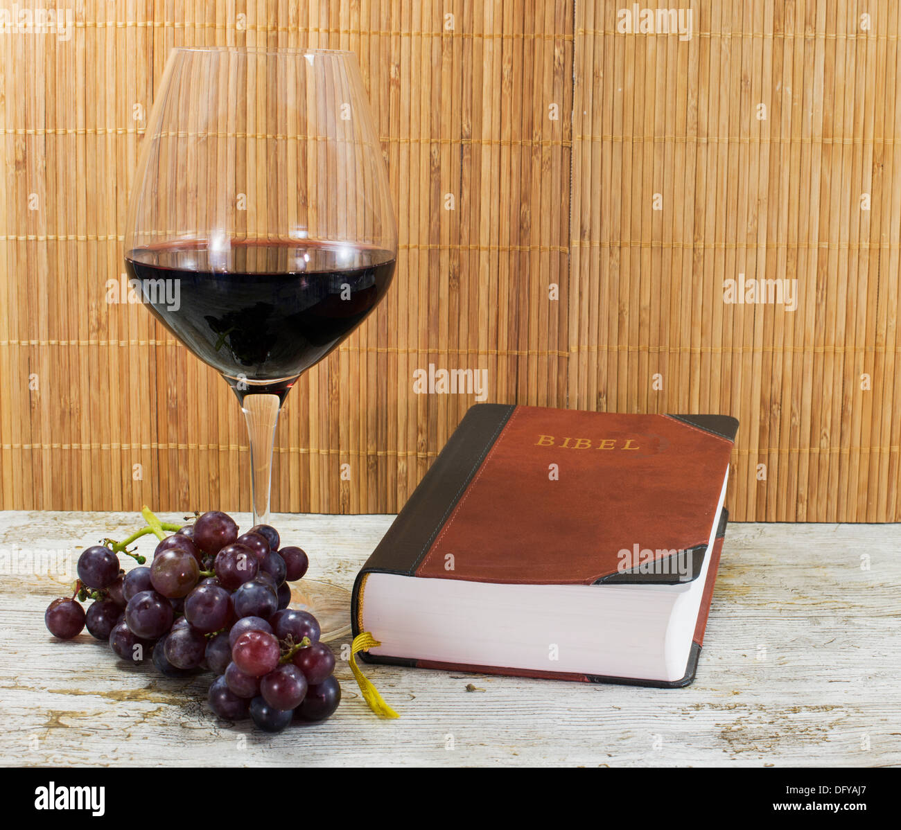 old bible and red wine with grapes on table Stock Photo