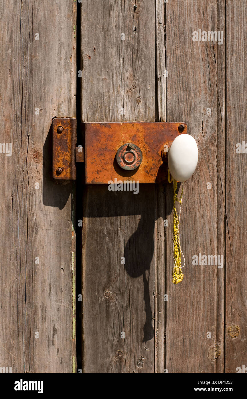 An Ancient Wooden Door with a Metal Grungy Lock and a White Handle. Stock Photo