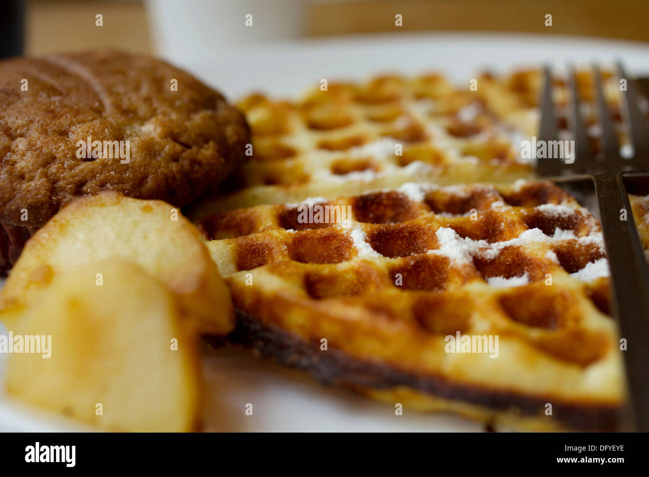 Waffles, Banana Chocolate Muffin And Grilled Potatoes served for breakfast. Powdered sugar is sprinkled on the waffle. Stock Photo