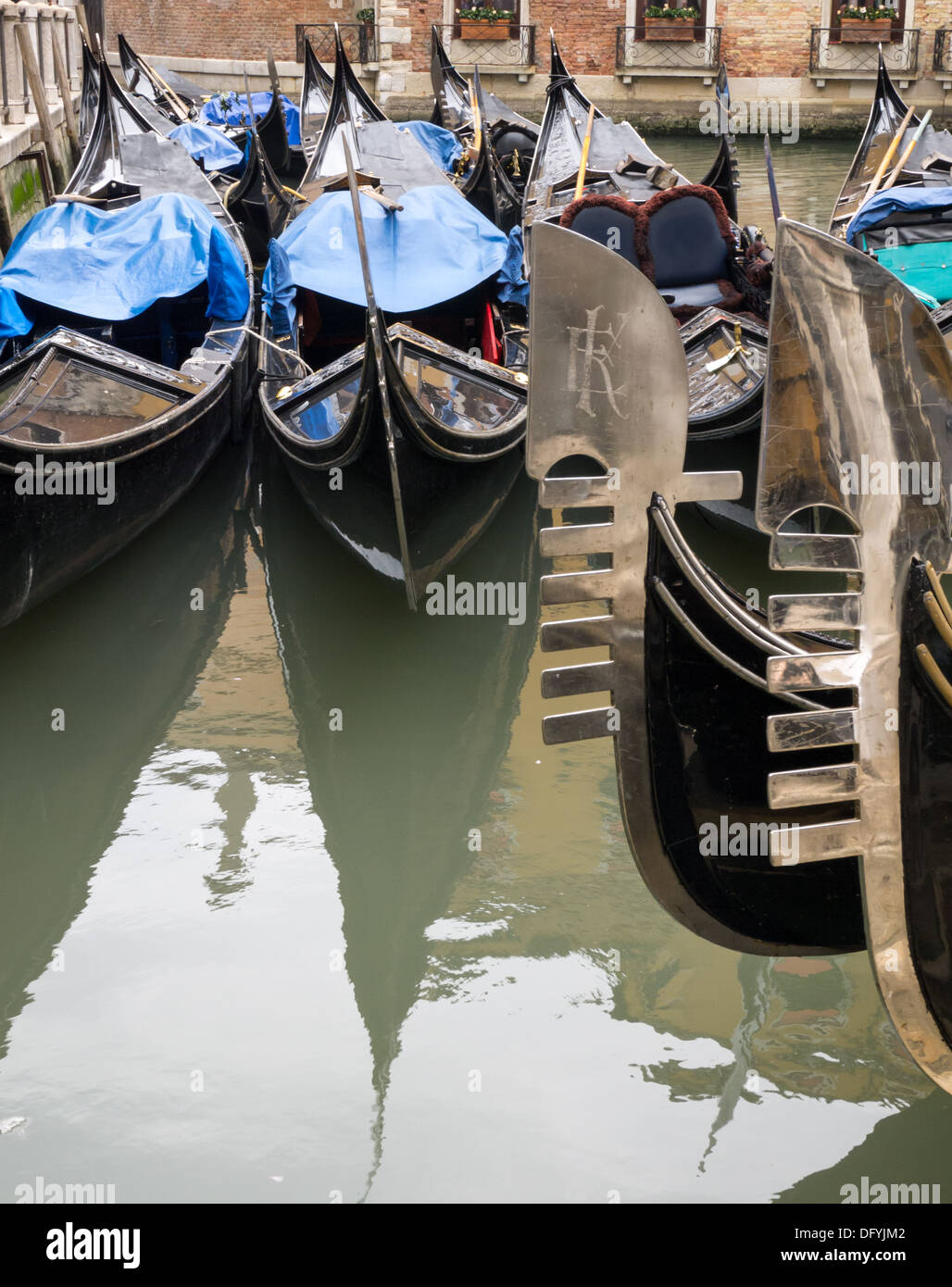 The shining six-toothed 'ferro' pieces on the prows of a number of Venetian gondalas and two more gondolas in the background Stock Photo