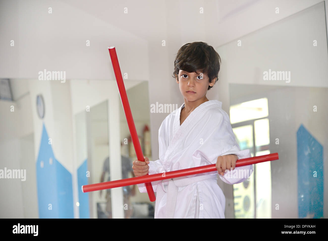Martial arts boy holding two red sticks called kali fighting sticks