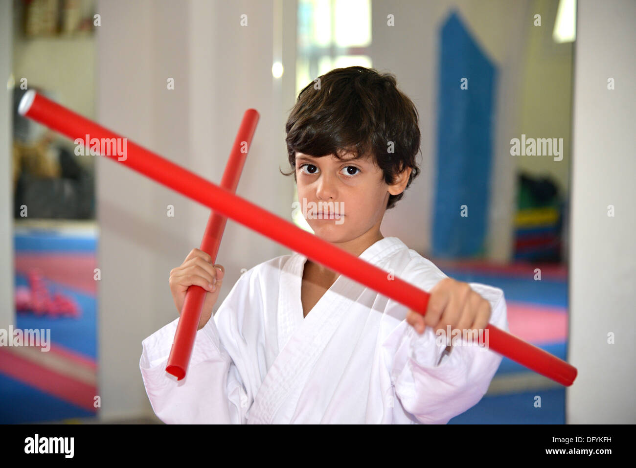 Martial arts boy holding two red sticks called kali fighting sticks