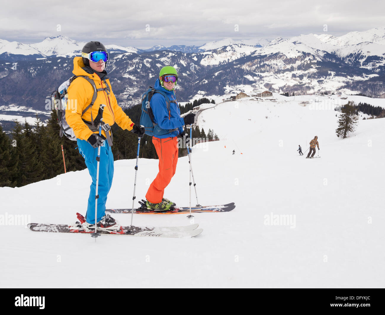 Two male skiers skiing in flat light on red run Marmotte in Le Grand Massif ski area of French Alps above Samoëns resort, France Stock Photo