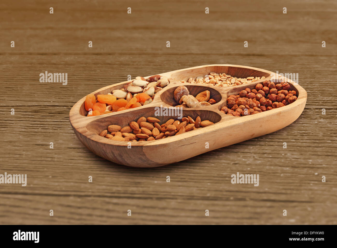 Hazelnuts, almonds and other different dried fruits in a wooden bowl Stock Photo