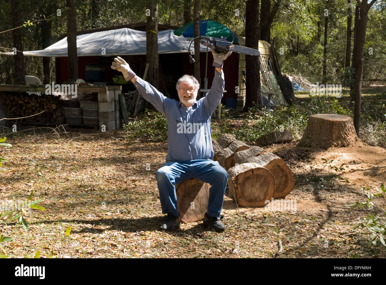 Man sitting on debris after success at cutting down a tree. Stock Photo