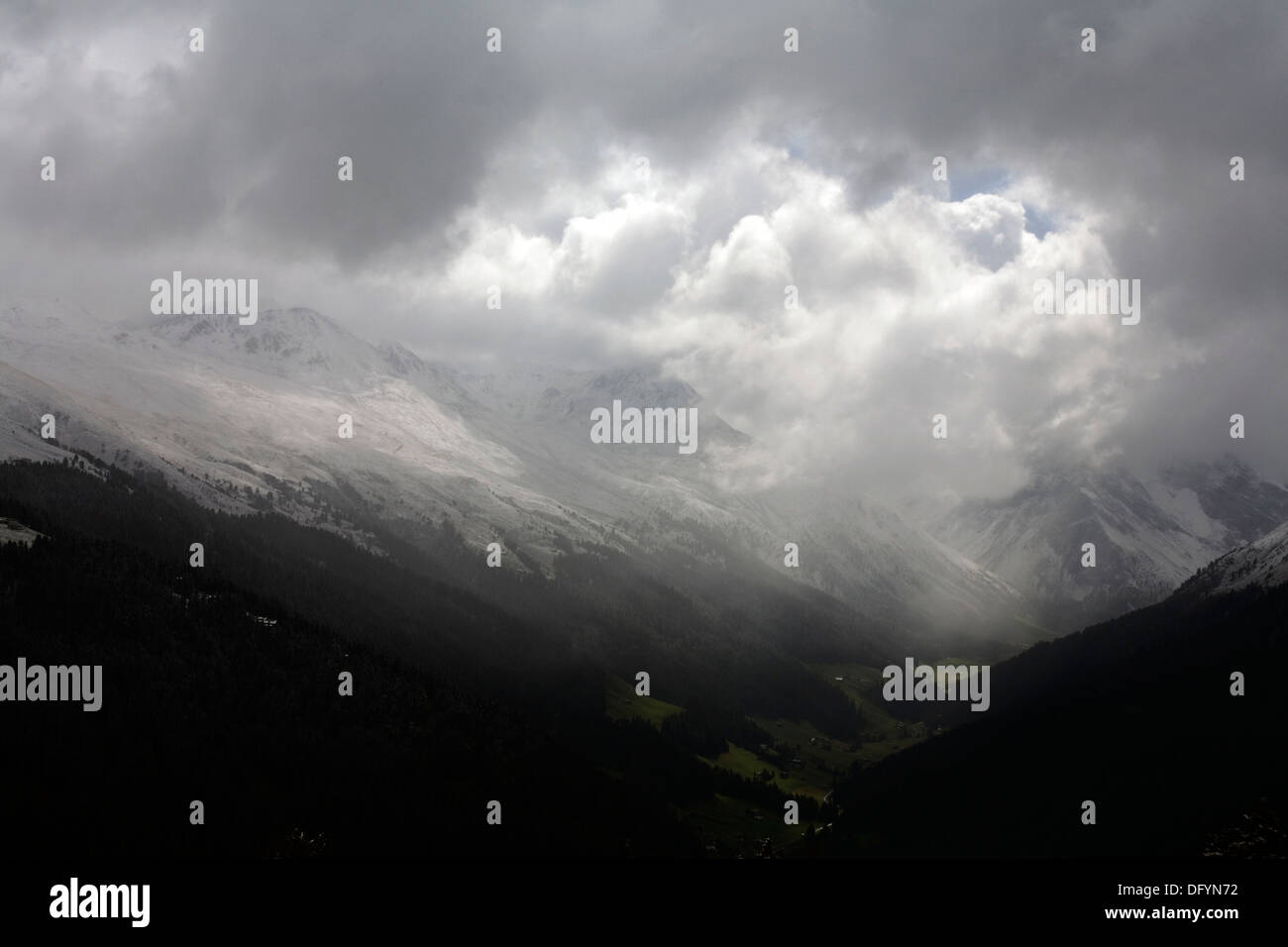 Shafts of sunlight and storm clouds passing over The Sertig Tal of The Landwasser Valley Davos Graubunden Switzerland Stock Photo