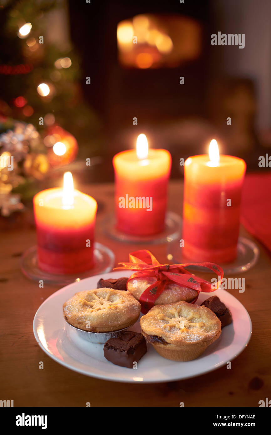 A Christmas tree scene at night with mince pies, lit candles and fire. Stock Photo
