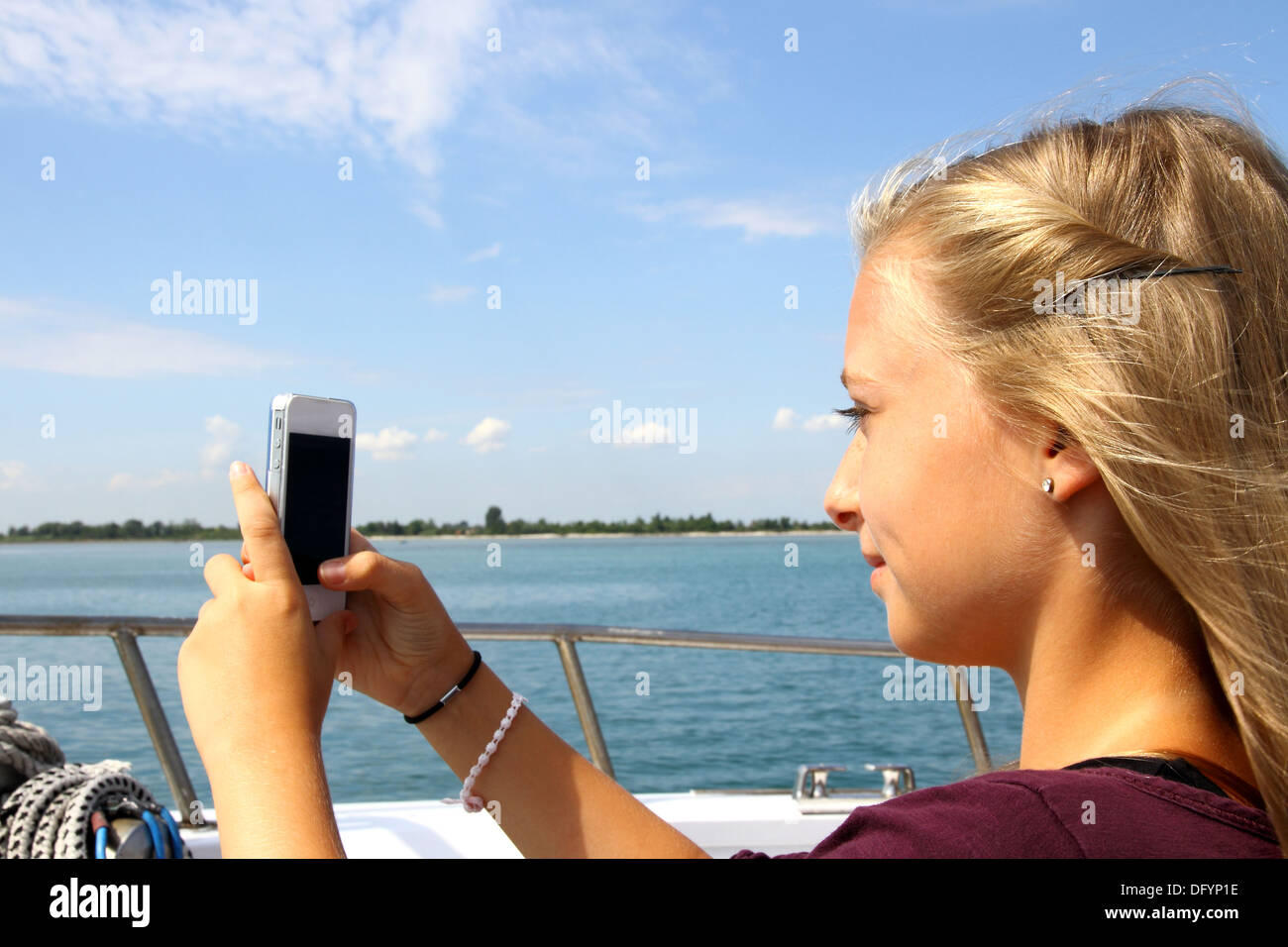 Smiling blond girl with phone on the boat, horizontal Stock Photo