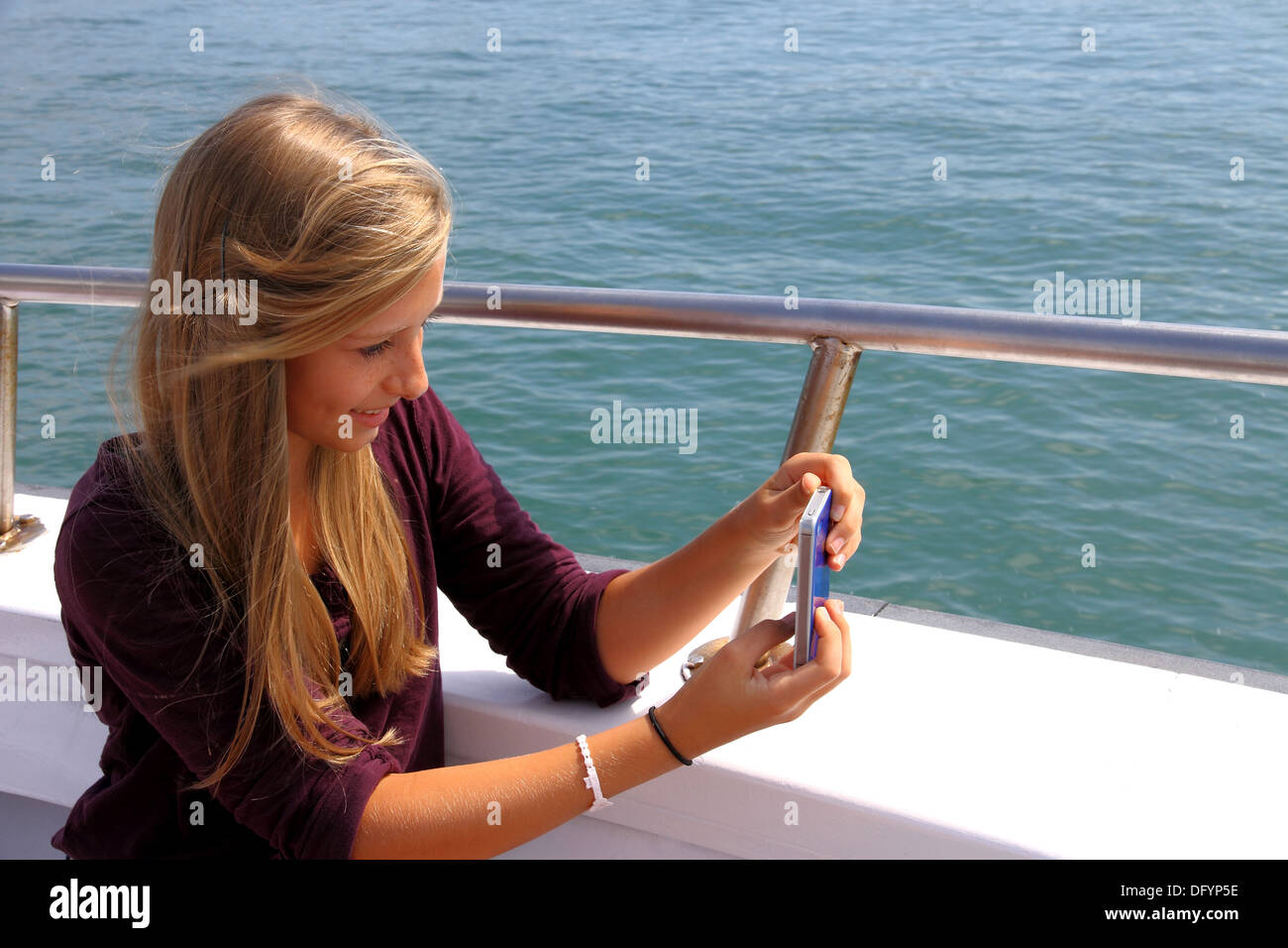 Happy blond girl with phone on the boat, horizontal Stock Photo