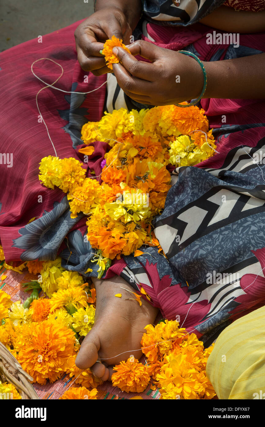 Rural Indian village woman sitting round a basket of marigold flowers making flower garlands. Andhra Pradesh, India Stock Photo