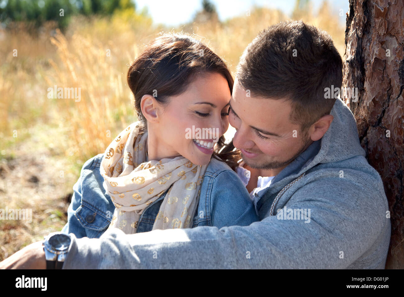 Outdoor close-up photo of young couple seated in grassy field. Stock Photo