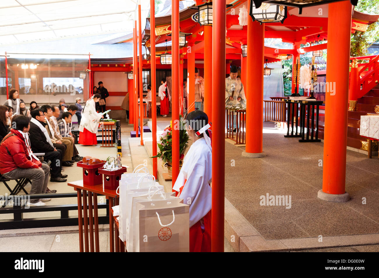 Ikuta shrine in Kobe, Japan at New Year. Shinto priest leading ceremonial blessing of  people seated, with Miko, shrine maidens on either side. Stock Photo