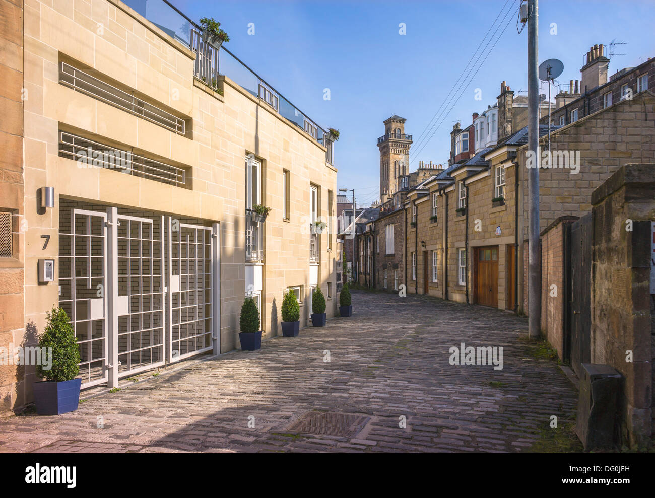 A small cobbled back street in Glasgow, old cottages jostle with the latest makeover houses provide an interesting street mix Stock Photo
