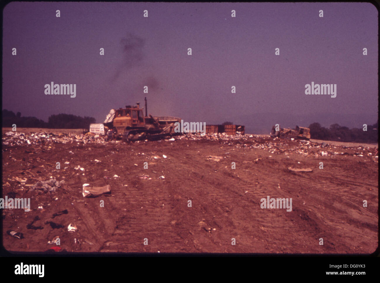 SPREADING AND COMPACTING GARBAGE BEFORE COVERING IT WITH ONE FOOT OF